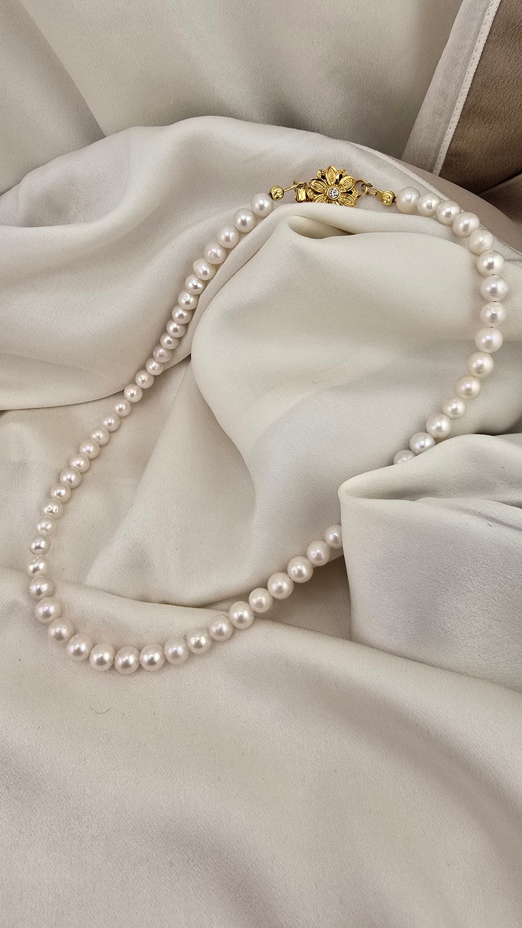 Necklace made of round, white cultured pearls in its case