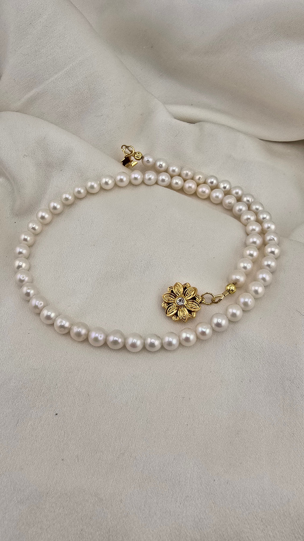 Necklace made of round, white cultured pearls in its case
