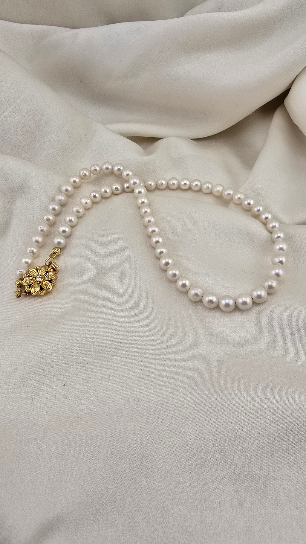 Necklace made of round, white cultured pearls in its case
