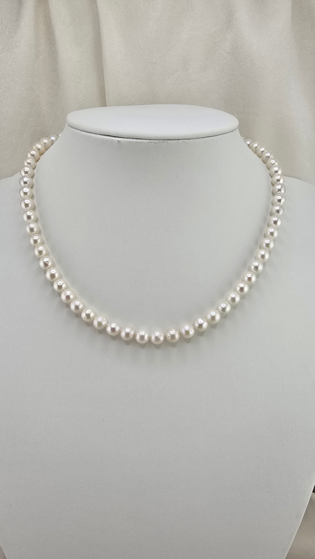 Necklace made of round, white cultured pearls in its case